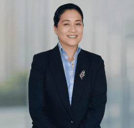 A woman in a suit and tie smiling for the camera.