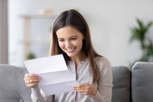 A woman sitting on the couch holding an open envelope.