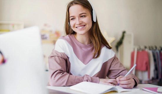 A girl with headphones on sitting at her desk