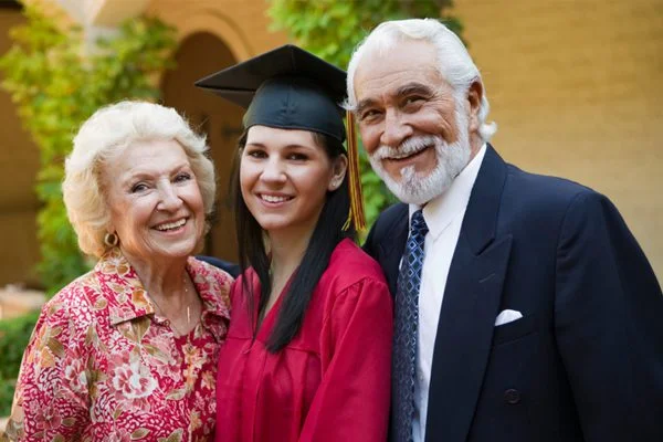 A woman in graduation gown with an older man and woman.