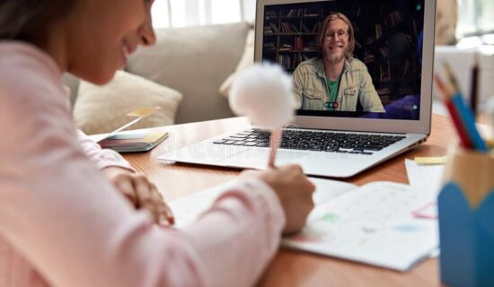 A girl is doing homework on her laptop.